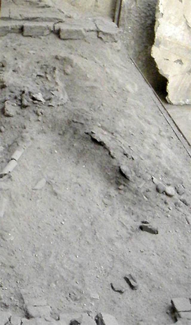 VI.21 Herculaneum. May 2009. Remains of skeleton lying on bed in “caretaker’s room”.