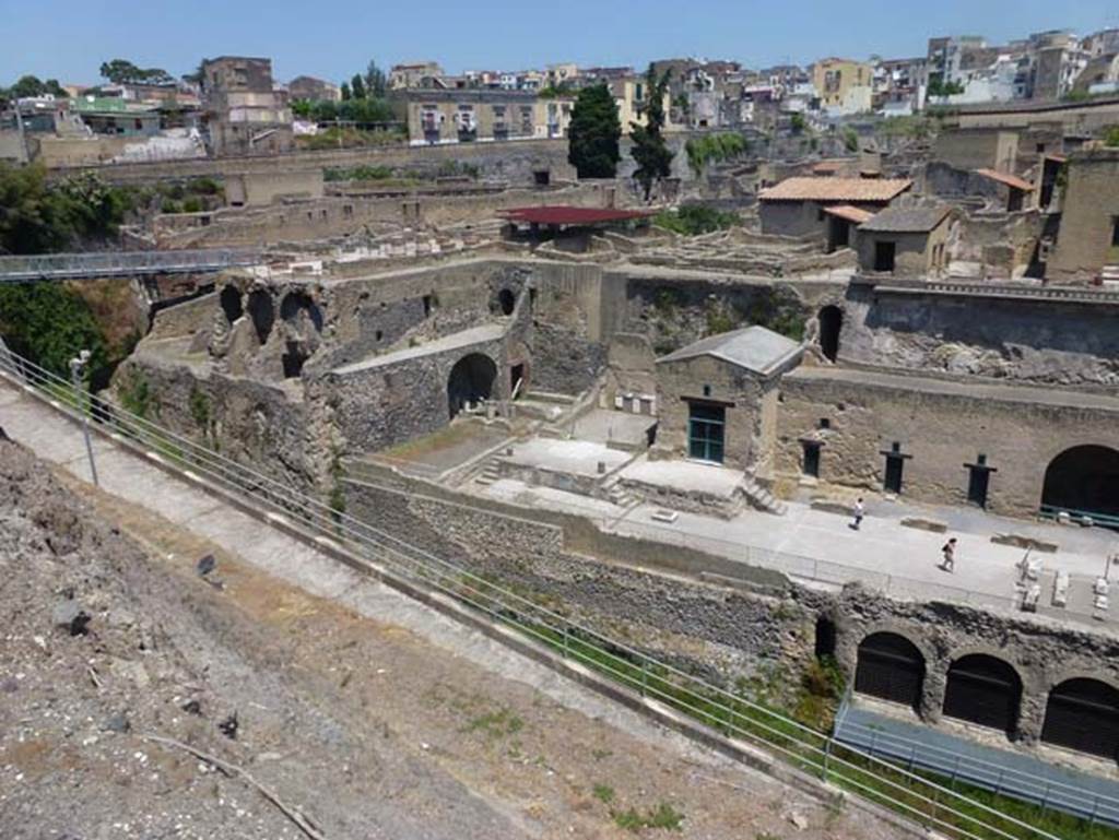 Herculaneum, June 2012. Looking north-west towards Sacred Area, below the town walls. 
The steps to a podium, in the centre, leads to a podium outside the doorway into the Shrine of Venus. 
On the left side of it, are more steps to another podium outside the Shrine of the Four Gods. Photo courtesy of Michael Binns.
According to Wallace-Hadrill –
“One of the benefactions of the great Nonius Balbus to his town was to repair the walls. 
We can see how he monumentalized the southern wall towards the sea, encasing it in a ‘network’ technique of opus reticulatum that was standard in the period of Augustus (see page 22). 
He may also have helped to improve the terraces beneath the walls. 
In any case, his statue and funerary altar were given pride of place on one of them by the entrance to the Suburban Baths.
To the west, there had already, probably since the second century BC, been a small temple, of which the podium has been glimpsed in an excavation.
This may be the temple of the goddess Herentas Erycina, the Oscan cult name of Venus, which is mentioned in the one surviving inscription in Oscan.
It was replaced, perhaps as part of Balbus’ programme, by two small temples, probably both dedicated to Venus.
Four handsome reliefs in the style of early Greek sculpture, showing the gods Minerva, Mercury, Neptune and Vulcan, do not necessarily indicate who was worshipped.”
See Wallace-Hadrill, A. (2011). Herculaneum, Past and Future. U.K, London, Frances Lincoln Ltd., (p.166).

