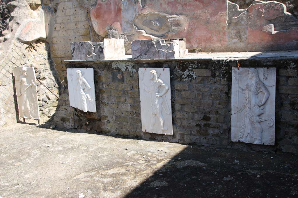 Herculaneum, April 2014. Sacred Area terrace, looking north in the shrine of the Four Gods.
The copies of the reliefs are thought to be hanging in their original position, fastened to the front wall of the podium. 
Photo courtesy of Klaus Heese.
