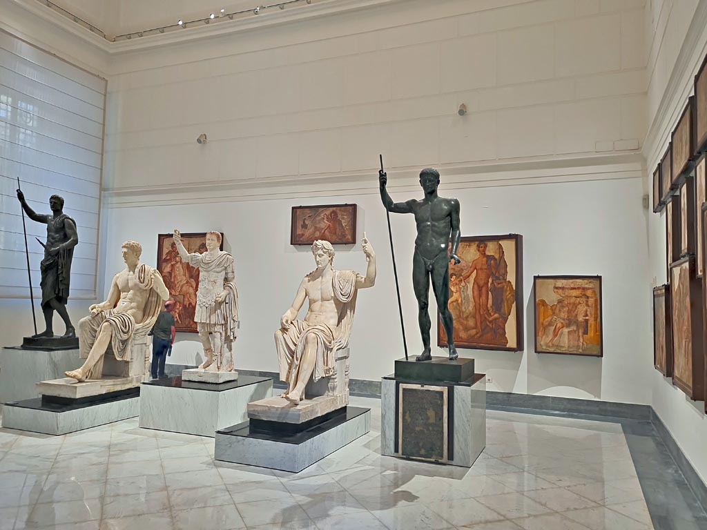 Herculaneum Augusteum. April 2023. 
Looking across gallery towards statues on display in “Campania Romana” gallery in Naples Archaeological Museum.  
(Note: the central statue of Titus has now been displayed).  Photo courtesy of Giuseppe Ciaramella.

