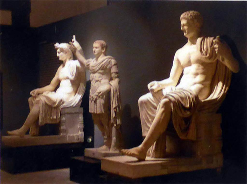 Herculaneum Augusteum. Square exedra. Statues displayed in their original layout.
The statues of the sitting Augustus (left), the standing breast-plated Titus, centre, and the sitting Claudius (right).
