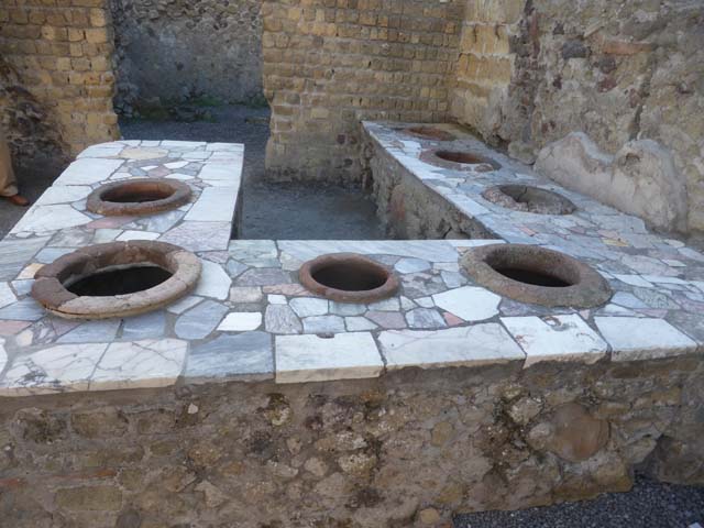 II.6/7 Herculaneum, September 2015. Looking south at northern end of counter/podium.  At the rear of the counter is the doorway leading into the two rear rooms.

