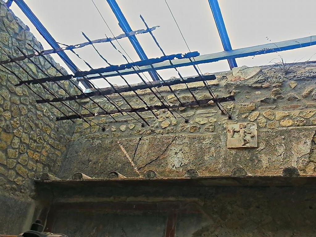 III.3 Herculaneum. Photo taken between October 2014 and November 2019. 
Marble relief of cupid on wall above the pool, with grating above. Photo courtesy of Giuseppe Ciaramella.


