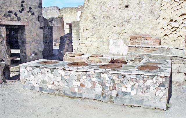 IV.16, Herculaneum, April 2018. Looking south-west across bar-counter towards doorways to rear rooms. Photo courtesy of Ian Lycett-King. Use is subject to Creative Commons Attribution-NonCommercial License v.4 International.
