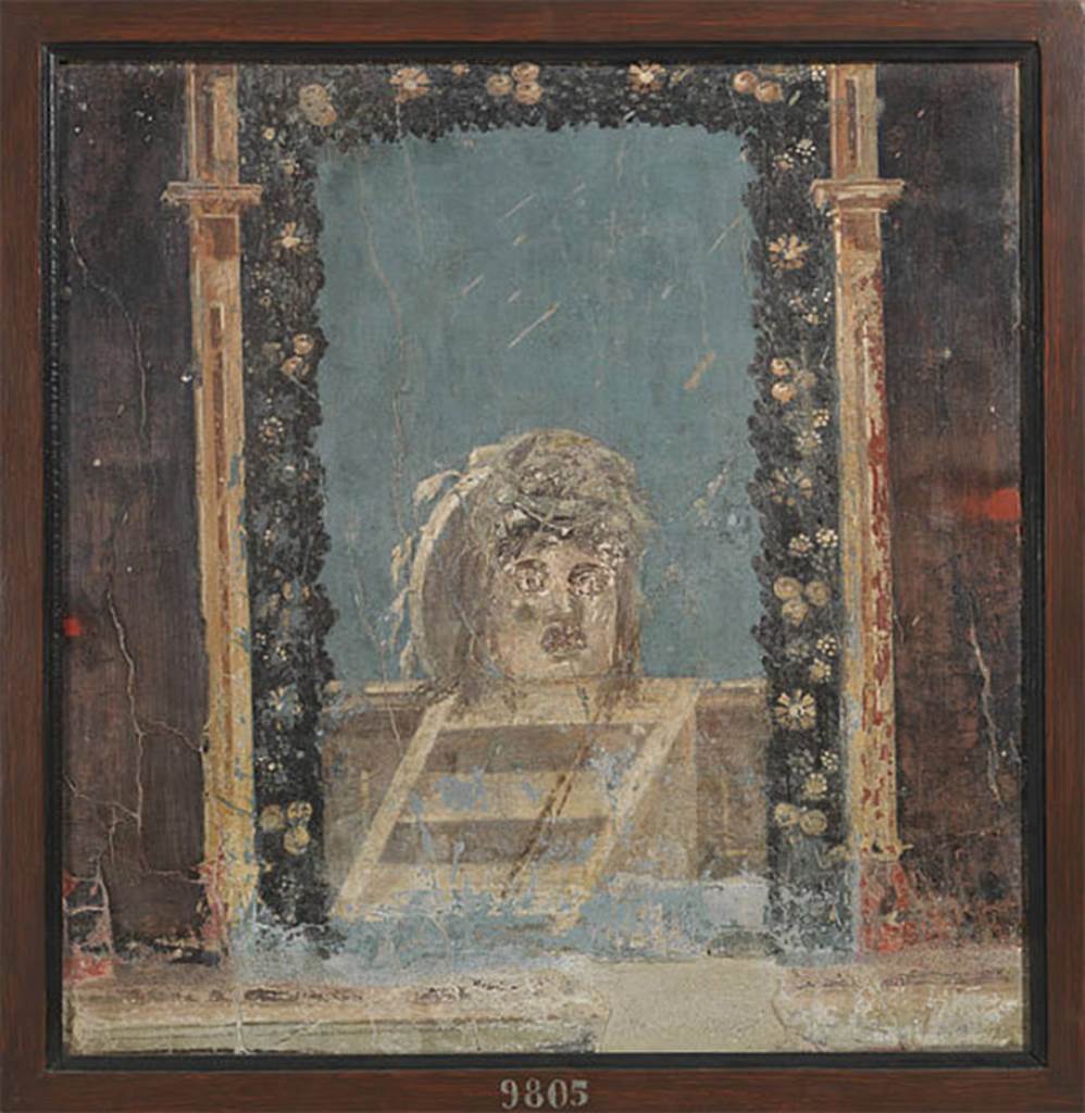 IV.21, Herculaneum. 1972. Triclinium 5, painting of Mask with thyrsus/lance nearby, originally found and detached from north wall plinth/dado/socle (zoccolo), on east end (right side).  
Detached and registered by Alcubierre, 20th June 1749, the first of 5 masks taken on 20th-21st June 1749.  
Now in Naples Archaeological Museum. Inventory number 9805.
