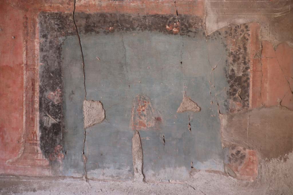 IV.21, Herculaneum. October 2020. Triclinium 5, zoccolo/dado at south end of east wall. 
Blue painted panel of masks, very badly faded, and left in situ. Photo courtesy of Klaus Heese. 
