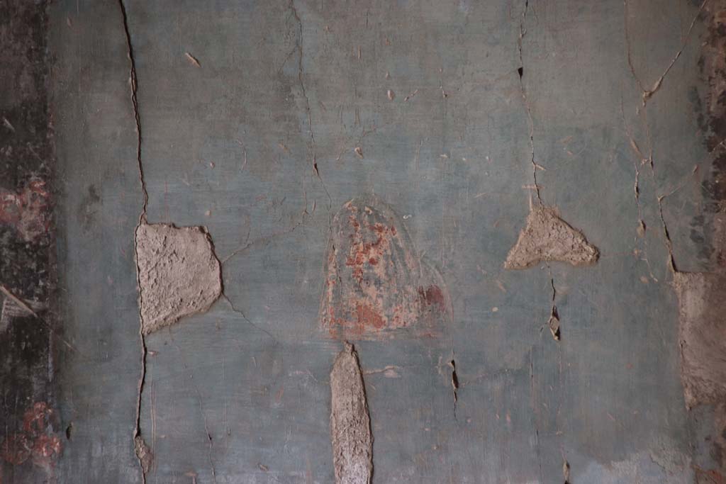 IV.21, Herculaneum. October 2020. Triclinium 5, zoccolo/dado at south end of east wall. 
Detail of blue painted panel of masks, very badly faded, and left in situ. Photo courtesy of Klaus Heese. 
