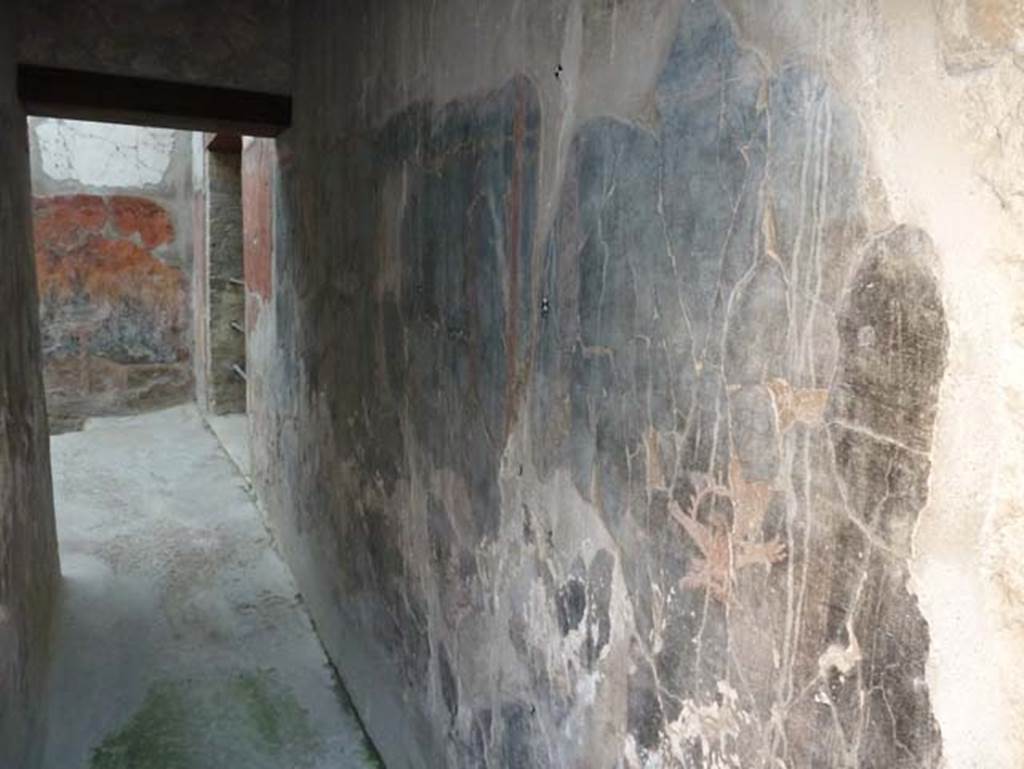 Ins. V 7, Herculaneum, September 2015. Looking along south wall of corridor leading to internal courtyard. At the far end is a doorway to the courtyard from the triclinium.
