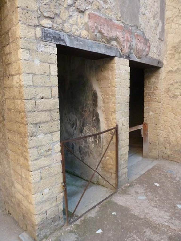 Ins. V 7, Herculaneum, September 2015. Two doorways in south-east corner of atrium.
The central one leads towards the internal courtyard (no access) and the other, on the right, leads into the triclinium.
