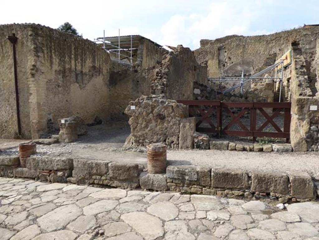 V.29, on left, and V.28, left of centre, and V.27 on right, Herculaneum, October 2014. Looking west on Cardo V. Superiore. These entrance doorways would have been sheltered under a portico, but only a small portion of the columns remain preserved in the pavement. Photo courtesy of Michael Binns.

