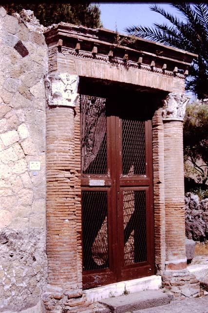 V.35 Herculaneum, House of Great Portal. 1964. Entrance doorway.
The name derives from the half-columns, and the brick lintel and cornice of the doorway.
Photo by Stanley A. Jashemski.
Source: The Wilhelmina and Stanley A. Jashemski archive in the University of Maryland Library, Special Collections (See collection page) and made available under the Creative Commons Attribution-Non Commercial License v.4. See Licence and use details.
J64f1168
According to Maiuri, the brick half-columns were originally stuccoed and painted red and are topped with Corinthian capitals adorned with winged Victories, and a decorated terracotta architrave above the door.
See Maiuri, A. Herculaneum, (No.53 of the series of Guide-books to Museums, Galleries and Monuments of Italy), (p.52)