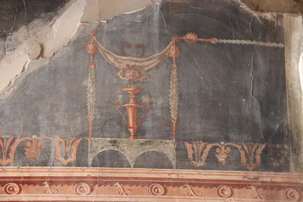 VI.13 Herculaneum. September 2017.  
Room 12, detail from upper west end of south wall of anteroom, with a painting of a gorgon’s head suspended from a garland above a vase.
Photo courtesy of Klaus Heese. 
