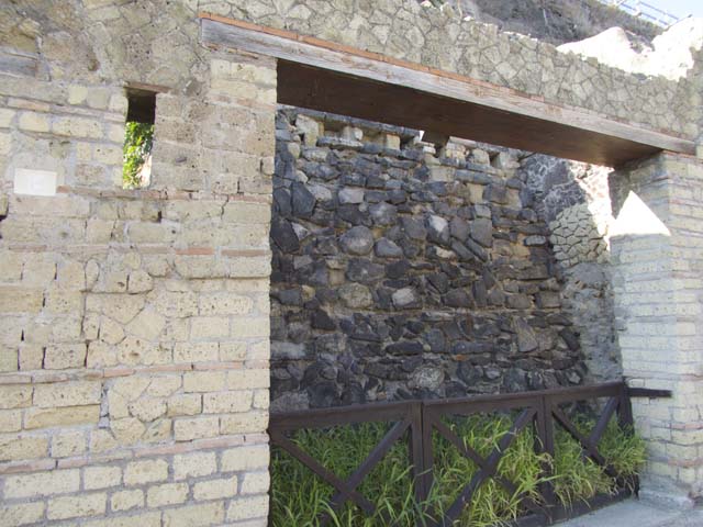 VII.7, Herculaneum, September 2015. Wide entrance doorway on west side of Cardo III, with wall at rear holding back unexcavated.  Photo courtesy of Michael Binns.
