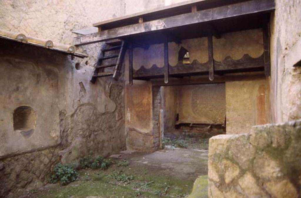 Ins. Orientalis II.9, Herculaneum. September 2015. Looking east across wine shop.
According to Deiss, “ the amphorae of wine were laid lengthwise on a supporting wooden scaffold, cut to fit their shape. They were reached by a ship’s ladder of wood, which now dangles in space, carbonised.”
See Deiss, J.J. 1968. Herculaneum: a city returns to the sun. UK, The History Book Club, (p.106).
