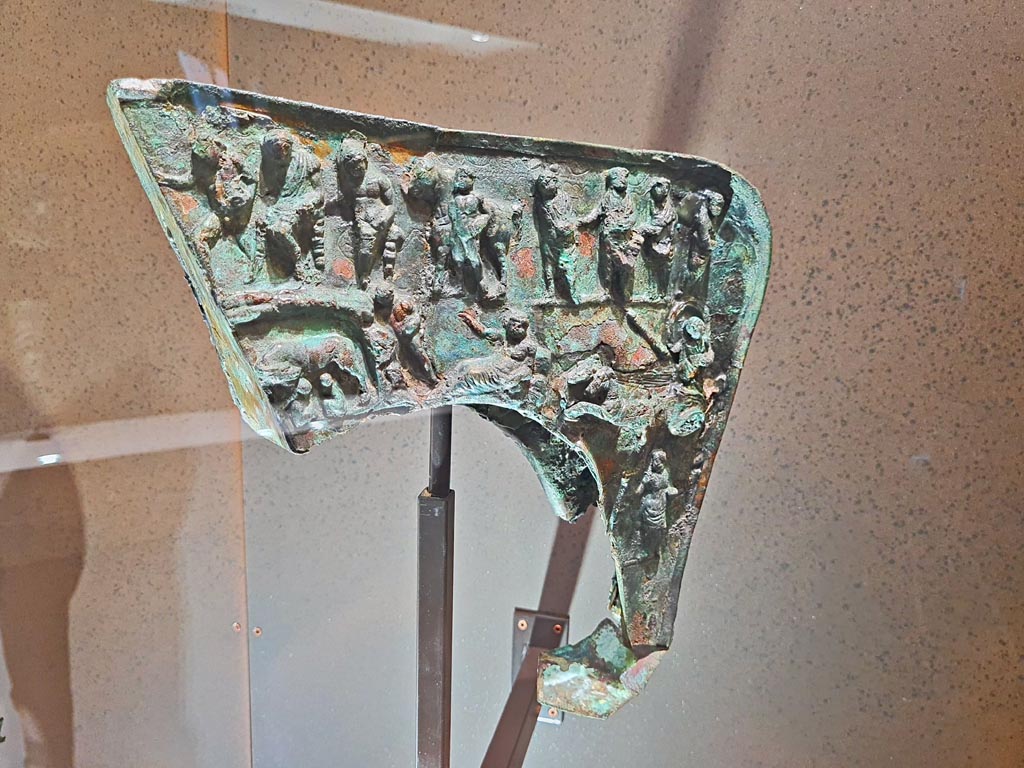 Found Herculaneum, 19th June 1834. Provenance unknown.
Bronze Mirmillo helmet crest with depictions of Mars, Rhea Silvia, she-wolf with Romulus and Remus and deities. 
May 2021. On display in Naples Archaeological Museum, inventory number 5673-5656. Photo courtesy of Giuseppe Ciaramella.
According to the Museum card –
The crest, which is the only part of this type of helmet found at Herculaneum, has a depiction of Mars who appears in a dream to Rhea Silvia, the she-wolf with the twins Romulus and Remus, the chariot of Aurora and, above, Jupiter seated on a throne among other figures.
The inventory number is shown as 5673-5656.
