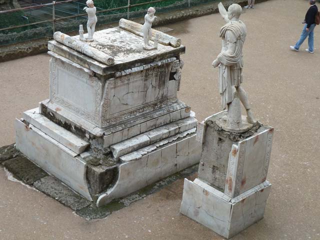 Herculaneum, September 2015. Memorial altar to Marcus Nonius Balbus together with his plaster-cast breast-plated statue, on the right. On the top of the altar stand two marble statues of sleeping funeral figures which would have been leaning on torches, which are now ruined.
