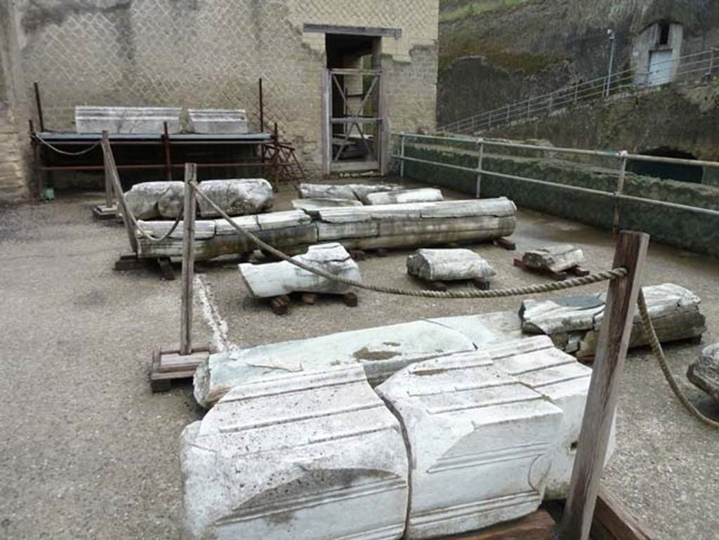 Herculaneum, September 2015. Sacred Area terrace, looking east towards doorway to large room 7 which contained a large podium against the north wall and masonry benches against the west and east walls. The remains of many columns and pilasters can be seen laid on the terrace floor.  Originally this was a large rectangular garden area in which two labra were found.
See Camardo, D, and Notomista, M, eds. (2017). Ercolano: 1927-1961. L’impresa archeologico di Amedeo Maiuri e l’esperimento della citta museo. Rome, L’Erma di Bretschneider, (p.284, Scheda 59).

