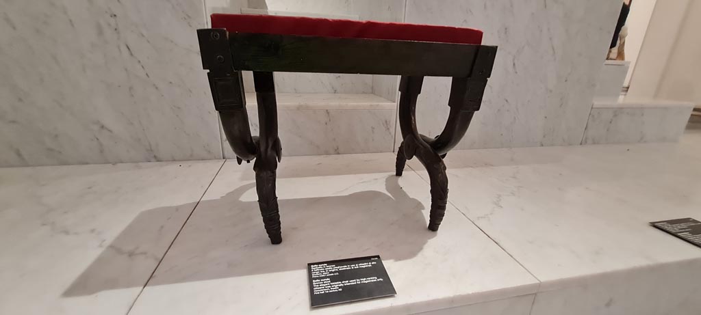 Herculaneum Theatre. April 2023. First bronze stool. Sella curule. Sgabello in bronzo n. 1.
Now in Naples Archaeological Museum, inventory number 73152. Photo courtesy of Giuseppe Ciaramella.
An honorific chair was set up in memory of Marcus Nonius Balbus.
A second honorific chair was set up for Appius Claudius Pulcher.


