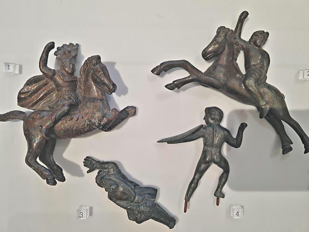 Herculaneum, April 2023. Bronzes in “Campania Romana” gallery in Naples Archaeological Museum. 
Detail of bronze figures in glass case - small bronze chariot attachments. Photo courtesy of Giuseppe Ciaramella.
