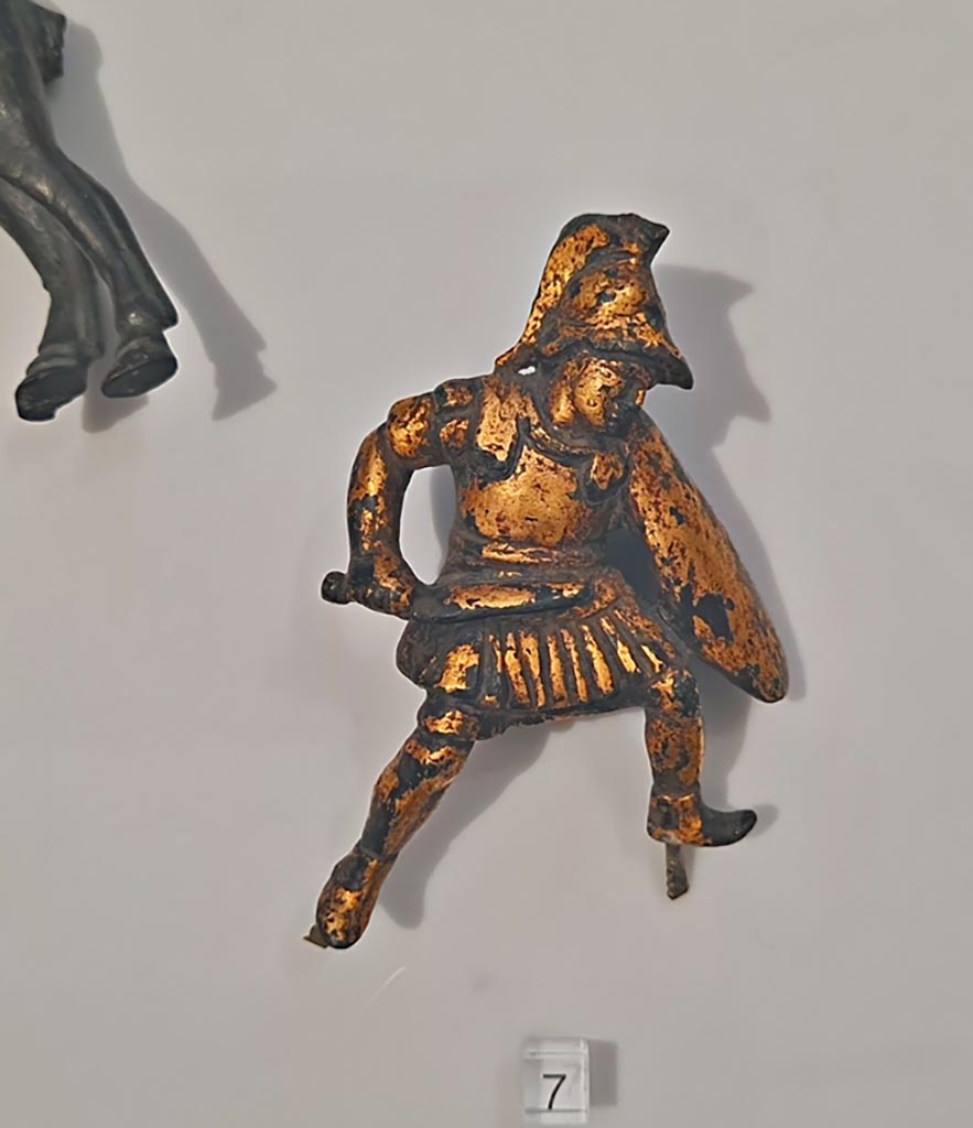 Herculaneum, April 2023. Bronzes in “Campania Romana” gallery in Naples Archaeological Museum. 
Detail of bronze figure in glass case - small bronze chariot attachment. Photo courtesy of Giuseppe Ciaramella.
