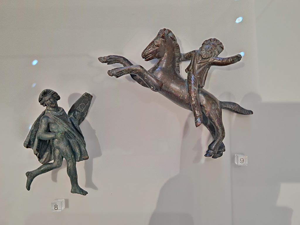 Herculaneum, April 2023. Bronzes in “Campania Romana” gallery in Naples Archaeological Museum. 
Detail of bronze figures in glass case - small bronze chariot attachments. Photo courtesy of Giuseppe Ciaramella.
