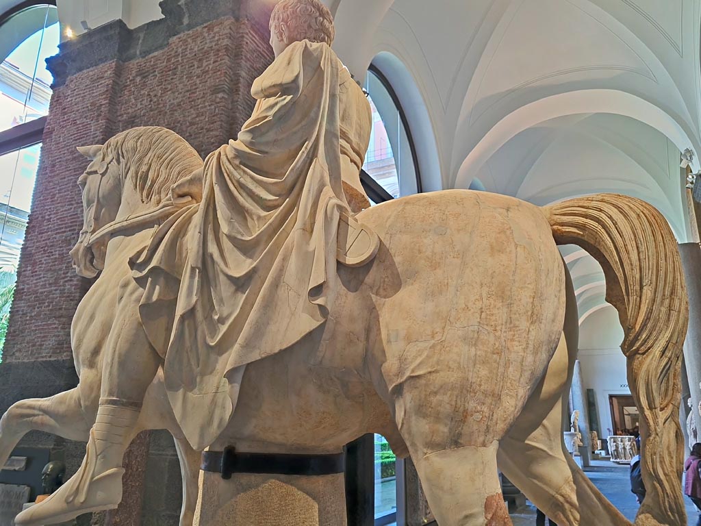 Herculaneum, public area. April 2023. 
White marble statue of Marcus Nonius Balbus, (inv. 6014), detail of cloak, shoes and rear of horse.  Photo courtesy of Giuseppe Ciaramella.

