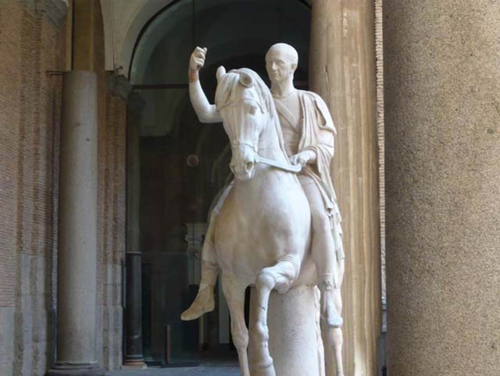 Herculaneum Theatre. May 2010. Equestrian statue of the elder M. Nonius Balbus.
Now in Naples Archaeological Museum. Inventory number 6211.
Photo courtesy of Buzz Ferebee.
According to the information board in the Palazzo Reale at Portici in 2015, the statue was found in 1746 and was in pieces and headless. 
The sculpture was believed to depict Balbus the Younger’s father. 
Hence, during restoration, Canart made head for it after a portrait certainly showing Balbus senior, in compliance with the principles of Classicism, which called for full restoration of mutilated sculptures. 
Actually, the two statues are believed to portray the same individual, being honoured respectively, by the towns of Nuceria and Herculaneum.