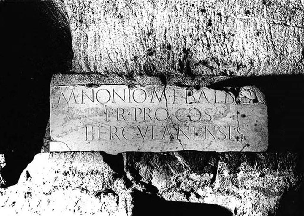 Herculaneum Theatre. Copy of inscription to M. Nonio M F Balbo, in situ underground.
M(arco) Nonio M(arci) f(ilio) Balbo
pr(aetori) proco(n)s(uli)
Herculanenses   [CIL X 1427]

“One base with the above inscription testifies the public gratitude of the city to that Marcus Nonius Balbus, and of whom we possess the equestrian statue found together with others of the same family in another public edifice, the so-called Basilica.”
See Maiuri, A, (1977). Herculaneum, (p.74).

According to Cooley and Cooley, this translates as
To Marcus Nonius Balbus, son of Marcus, praetor, proconsul, the people of Herculaneum.
See Cooley, A. and M.G.L., 2014. Pompeii and Herculaneum: A Sourcebook. London: Routledge, D66, p. 94.
This inscription, opposite that for Appius Claudius Pulcher, may mark the place where an honorific chair was set up in memory of Marcus Nonius Balbus.
A second honorific chair was set up for Appius Claudius Pulcher.
