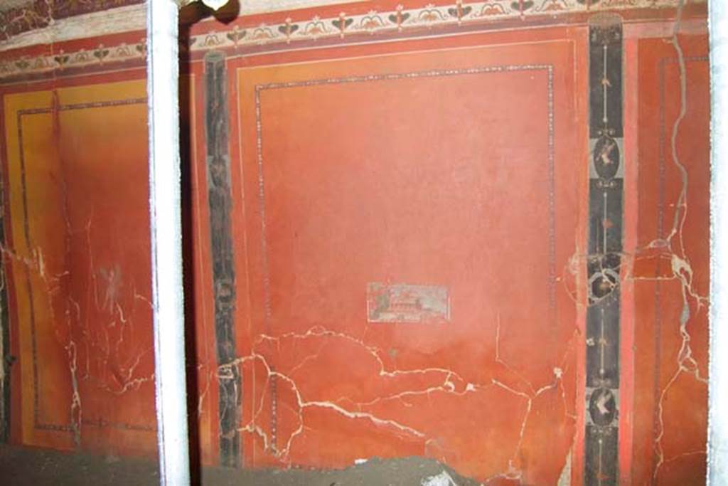 Villa dei Papiri, Herculaneum. July 2010. Room (I) on lower terrace, lower south wall. The short walls like this one have three panels and the long walls have 5 panels. The original yellow background, visible here, has turned red because of the dehydration that the exceptional temperature of the eruption caused. 
The centre of this wall is decorated with a small villa scene and on either side are vignettes with flying cupids.
Photo courtesy of Michael Binns.
See Esposito D. and Guidobaldi M., 2010. New Archaeological Research at the Villa of the Papyri, in the Villa of the Papyri at Herculaneum. Berlin: De Gruyter, p. 35. 



