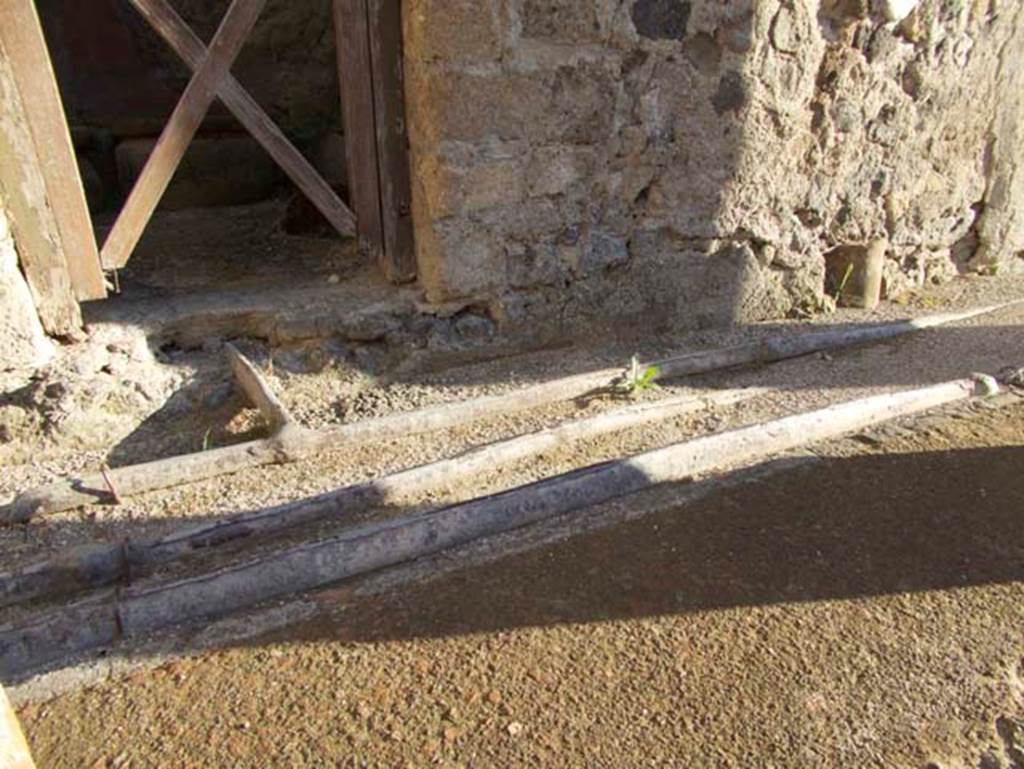 V.9 Herculaneum, September 2015. Looking east to doorway, across line of lead pipes in pavement.  Photo courtesy of Michael Binns.
